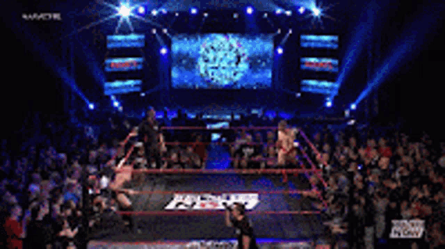 two men are wrestling in a ring with a sign in the background that says wow