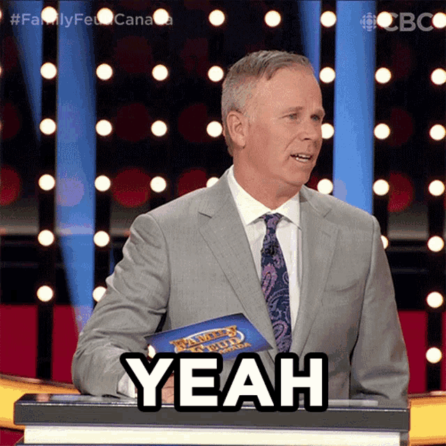 a man in a suit and tie stands at a podium with the word yeah on it