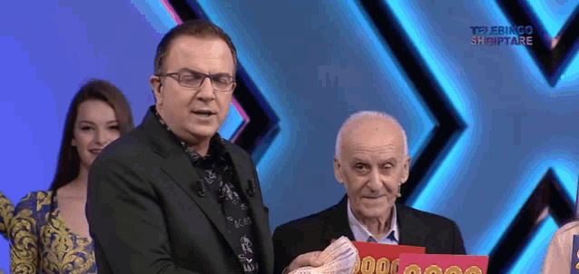 a man in a suit stands next to a man holding a sign that says 900 000