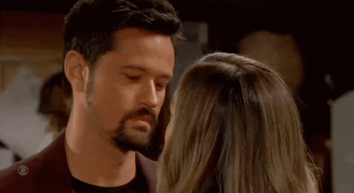 a man and a woman are looking into each other 's eyes and kissing .