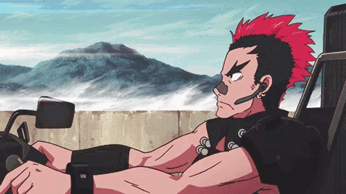 a man with a red mohawk sits in a car with mountains in the background
