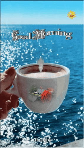 a person holding a cup of coffee in front of the ocean