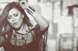a black and white photo of a woman holding her hair .