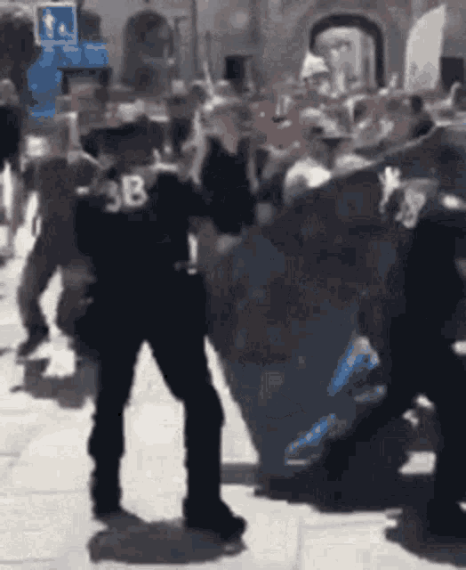 a man wearing a sb shirt is dancing in front of a crowd of people