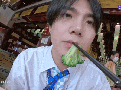 a man in a tie is eating broccoli with chopsticks in a video recorder