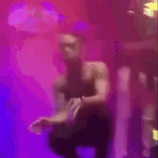 a blurry picture of a person dancing on a stage with a pink background .