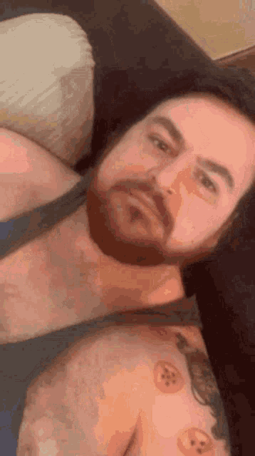 a shirtless man with a beard is laying on a couch .