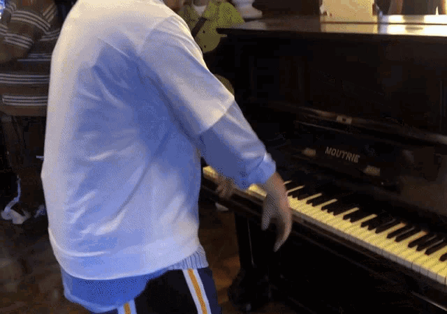a man playing a moutrie piano in a white shirt