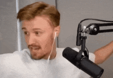 a man with a beard is standing in front of a microphone wearing headphones .