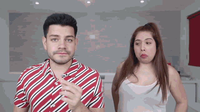 a man wearing a red and white striped shirt stands next to a woman