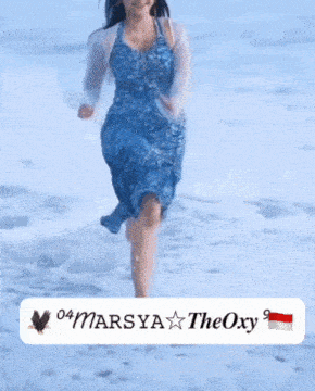 a woman in a blue dress is running on a beach with the name marsya theoxy