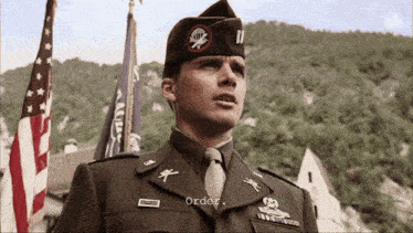 a man in a military uniform stands in front of an american flag and the word order is on the screen