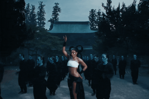 a woman in a white top is dancing in front of a crowd of people