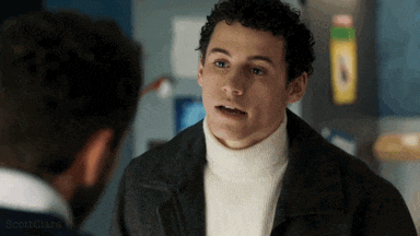a man wearing a turtleneck and a jacket is talking to another man