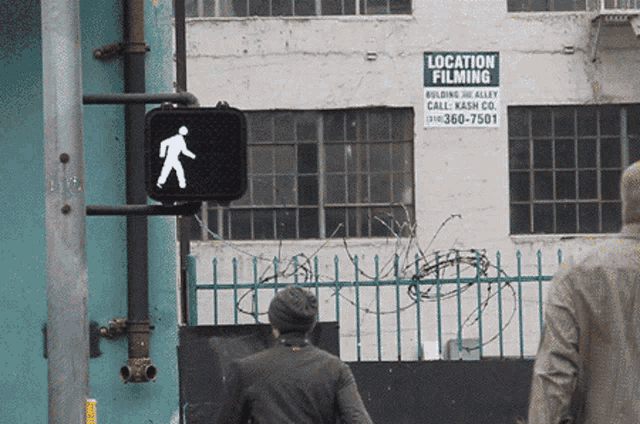 a sign for location filming hangs on a pole