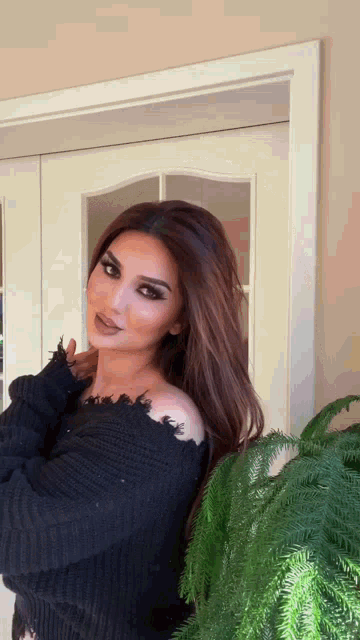 a woman wearing a black off the shoulder sweater is standing in front of a door