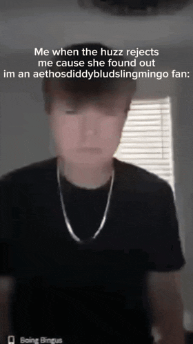 a young man wearing a black t-shirt and a silver chain .