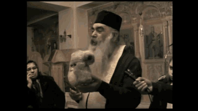 a man with a beard is holding a stuffed animal in his hand