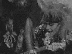 a black and white photo of two people singing into microphones .