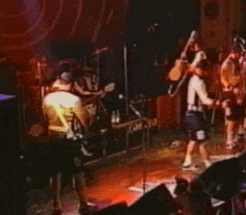 a group of people are playing instruments on a stage in a dark room