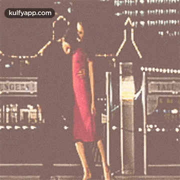 a woman in a red dress is being lifted by a man in a red shirt in front of a sign that says staff