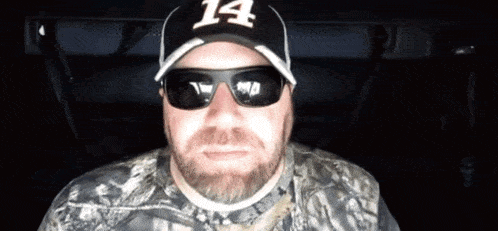 a man wearing sunglasses and a hat with the number 14