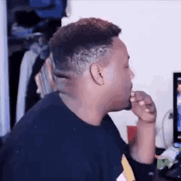 a man is sitting in front of a computer and eating a candy bar .