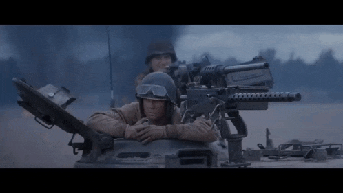 a man in a helmet sits on top of a tank with a gun