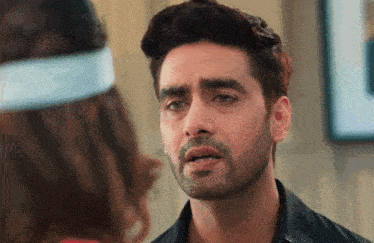 a man with a beard is looking at a woman with a headband on her head .