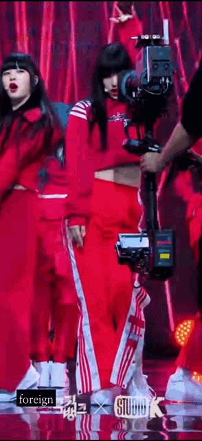 a woman in red pants is being filmed by a camera while dancing on a stage .