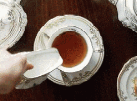 a cup of tea is being poured into a saucer on a table