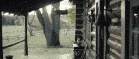 a log cabin with a porch and a fence in the background