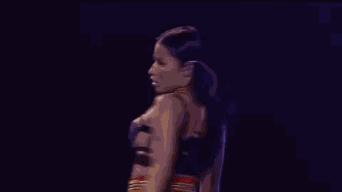 a woman is standing on a stage wearing a black bra .