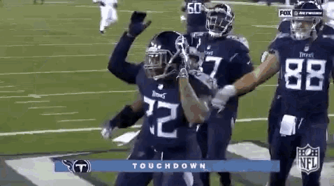 a group of football players are standing on a field celebrating a touchdown .