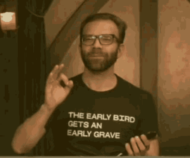a man wearing a black t-shirt that says the early bird gets an early grave