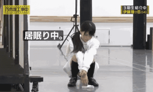 a woman is squatting on the floor with a sign above her that says " sleeping "