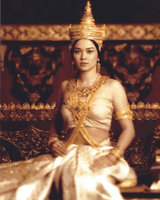 a woman in a white and gold costume is sitting on a chair