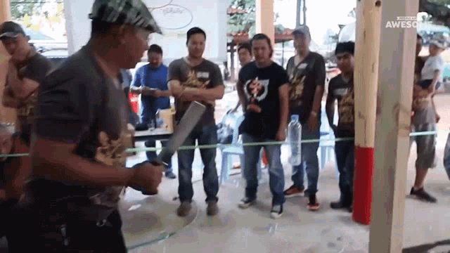 a man is holding a large knife in front of a group of people with awesome written on the bottom right corner