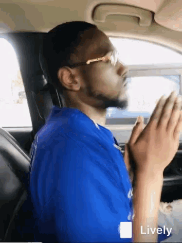 a man in a blue shirt is praying in a car with the word lively on the bottom right