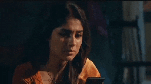 a woman is crying while holding a cell phone in her hands .