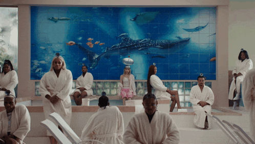 a group of people in bathrobes are sitting in front of a whale shark wall