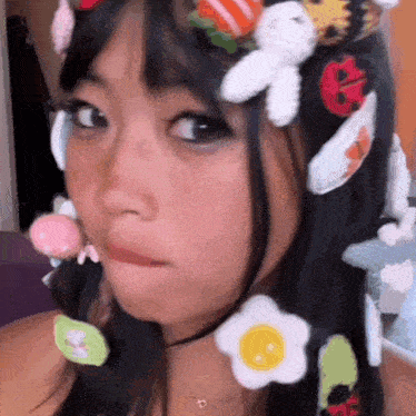 a close up of a girl wearing a hat with a bunch of stuffed animals in her hair .