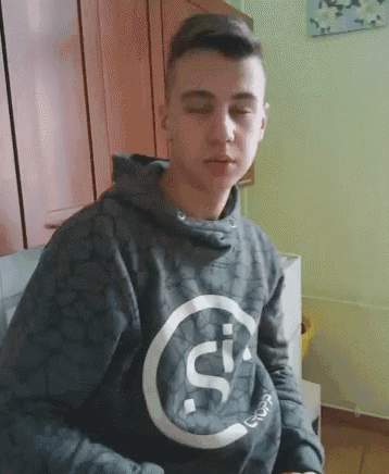 a young man wearing a grey sweatshirt with the letter s on the front