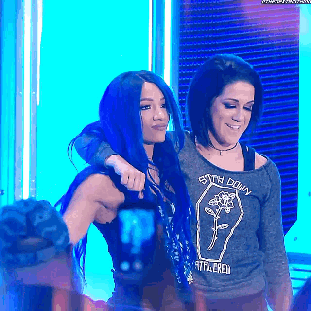 two women are posing for a picture and one has a shirt that says stay down