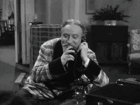 a man in a plaid robe is sitting at a table talking on a telephone