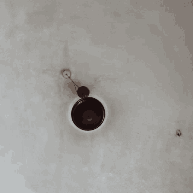 a black object is hanging from a ceiling with a cord