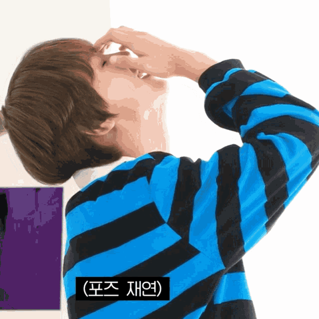 a man in a blue and black striped shirt is covering his nose
