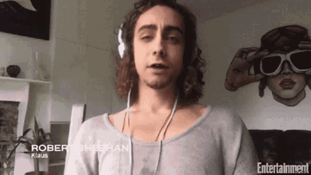 a man wearing headphones has the name robert sheehan written on his shirt