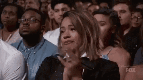 a woman is sitting in a crowd of people applauding .