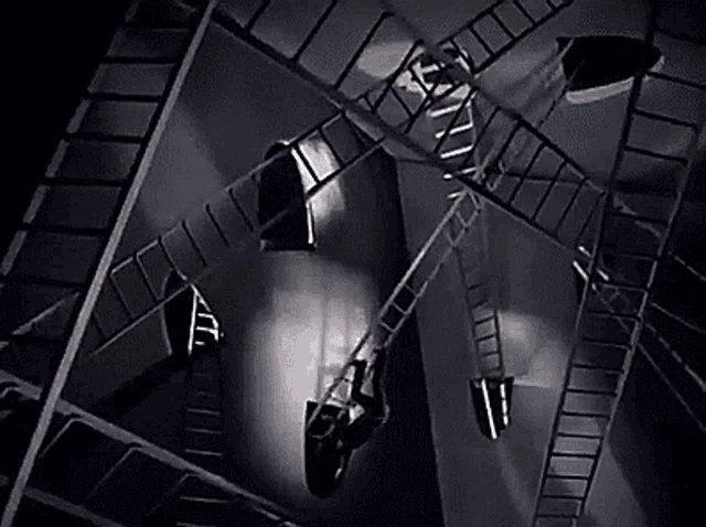 a black and white photo of a person hanging from a ladder in a dark room .